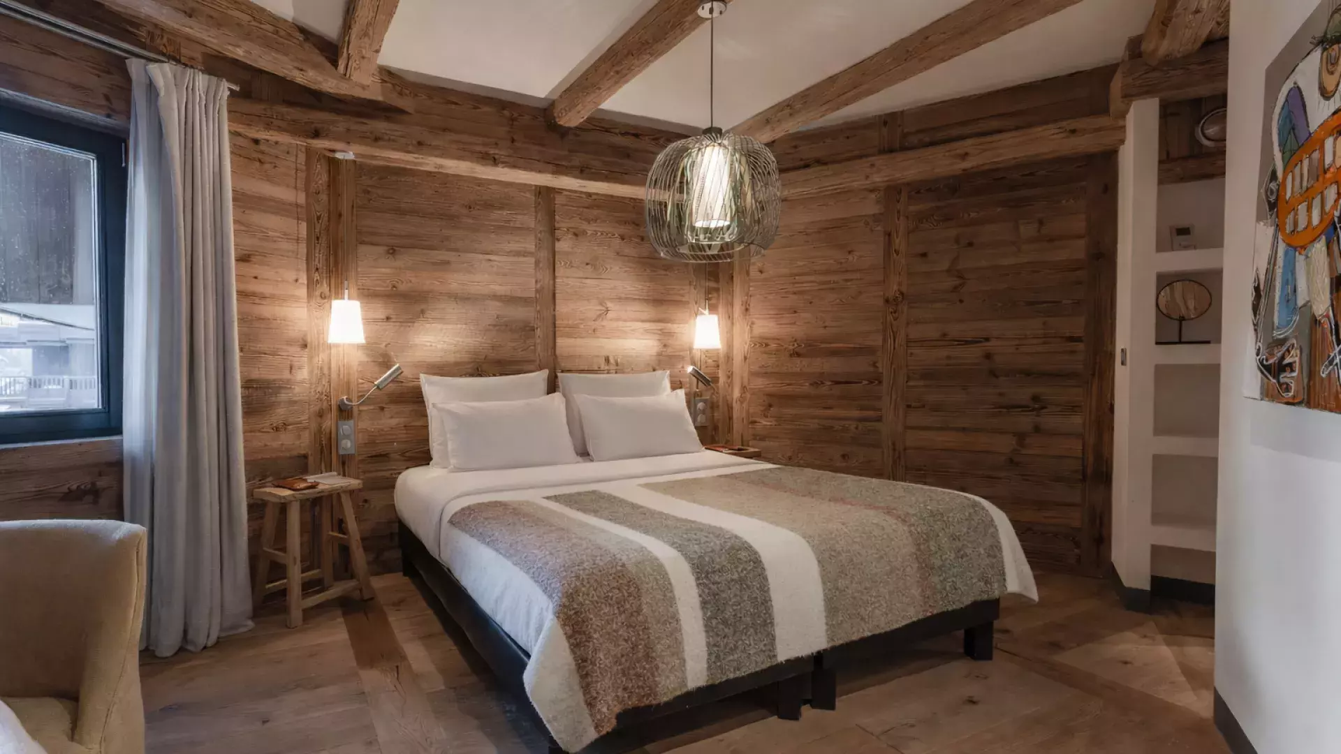 Chambre double intimiste habillée de vieux bois avec suspension design et touche d'art contemporain au Penthouse Savoie.