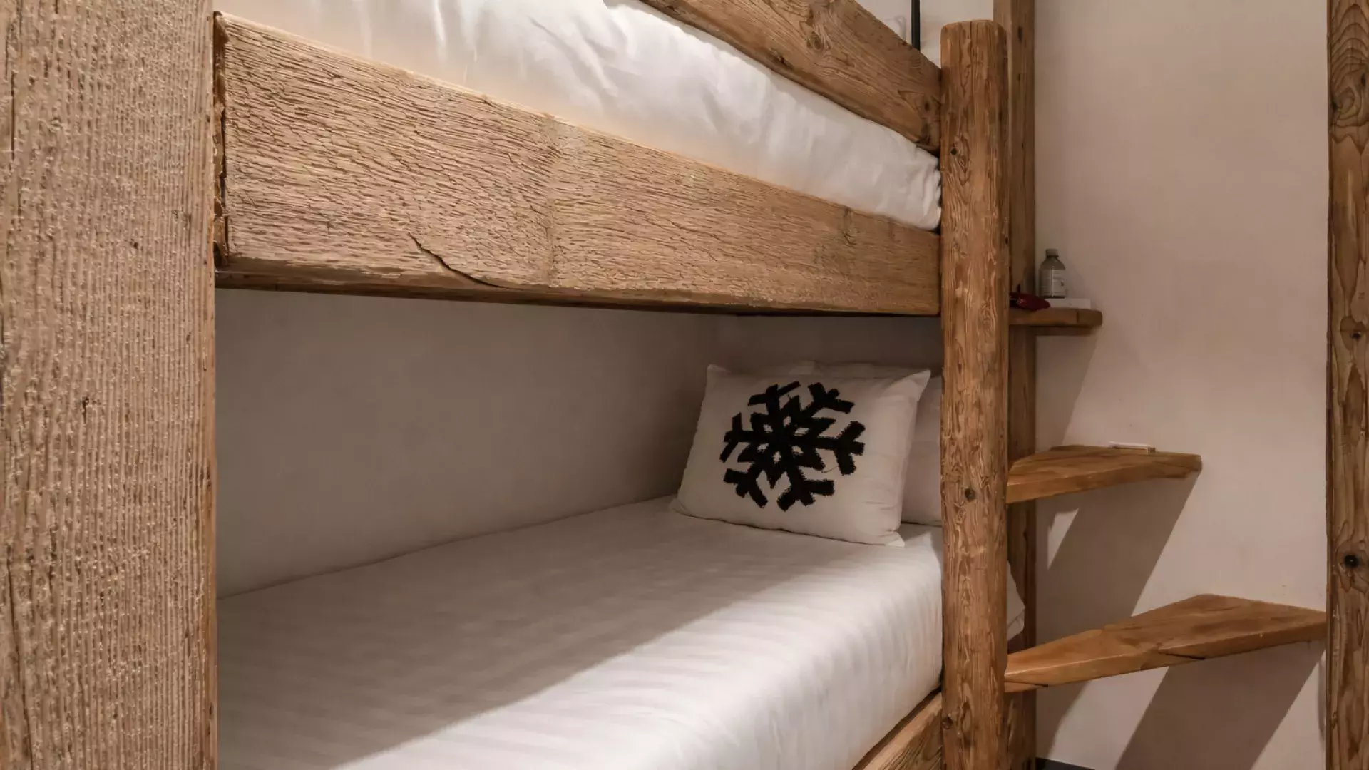 Lits superposés en bois brut style chalet avec échelle intégrée et coussin motif flocon dans la chambre dortoir du Penthouse Savoie.