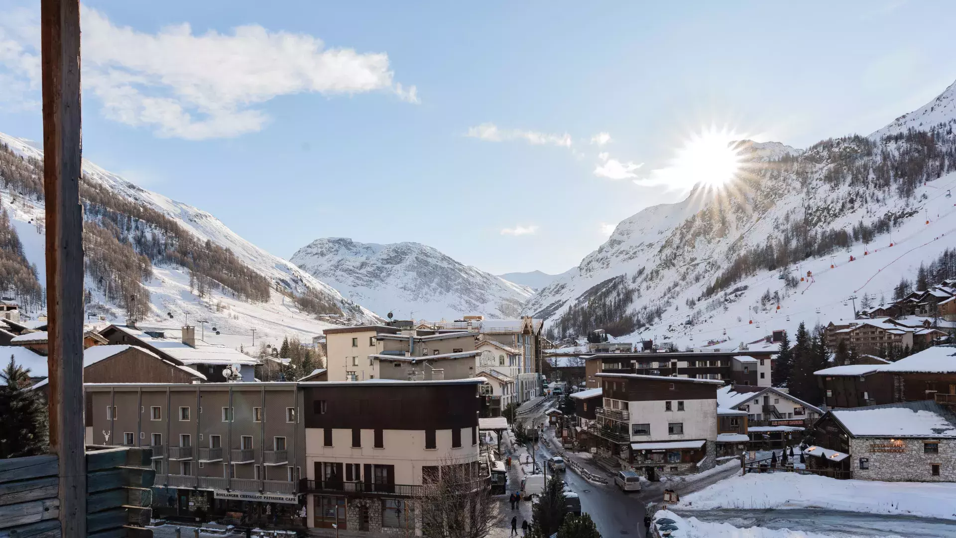 Vue panoramique ensoleillée sur le village de Val d'Isère et les sommets enneigés depuis le balcon du Penthouse Savoie.
