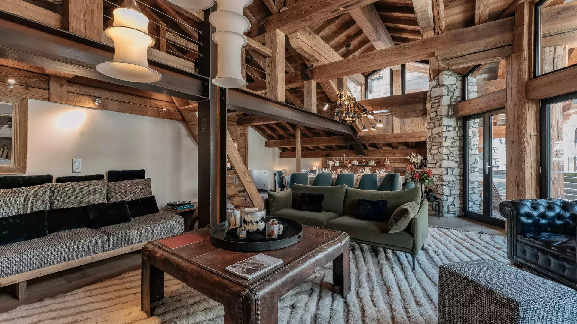 Grand salon cathédrale spectaculaire avec charpente apparente, canapés design en velours et cuir, et table basse coffre au Chalet Face.
